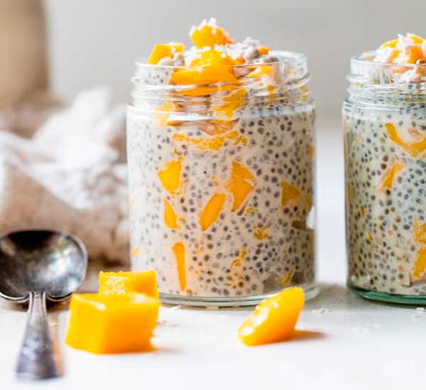 Pai e filho comem sobremesa com sementes de chia e manga à beira da piscina  pela manhã. alimentação saudável, comida vegetariana, dieta e conceito de  pessoas